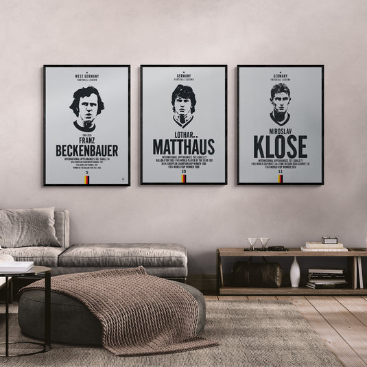 Three framed posters of famous German footballers on a wall in a living room.